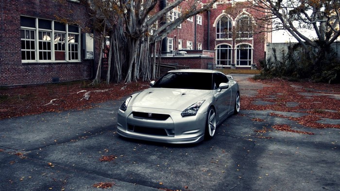 Silver Nissan GT-R parked in front of a brick building