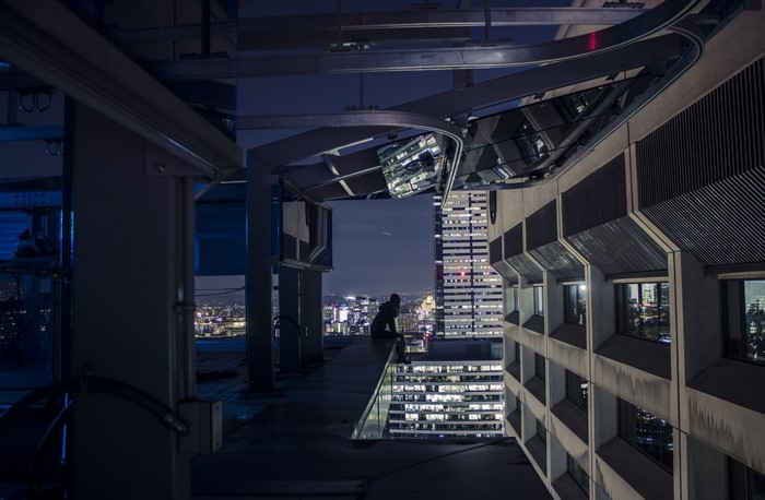 Person on a rooftop overlooking a cityscape at night