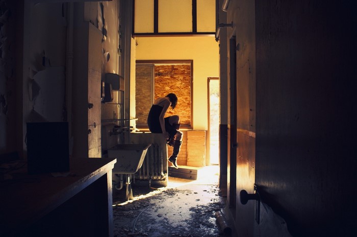 Woman sitting in a derelict room with sunlight streaming in