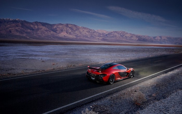Red McLaren P1 driving on a desert road at sunset