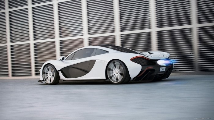 White McLaren P1 driving past a modern building