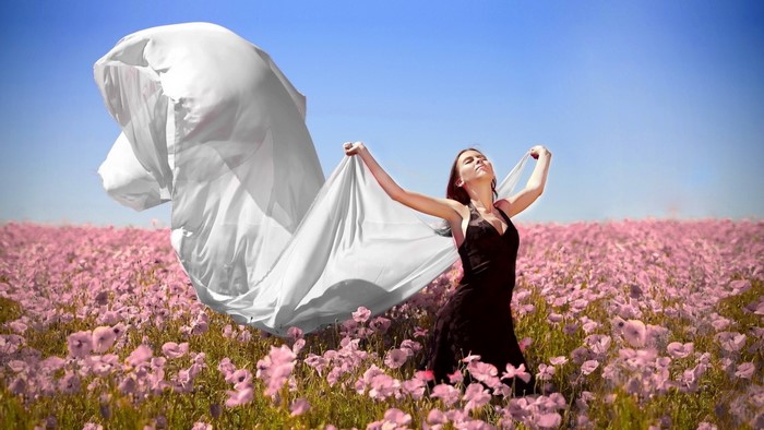 Woman in black dress holding white fabric in flower field