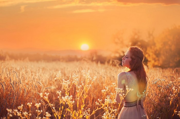 Woman in a wheat field at sunset