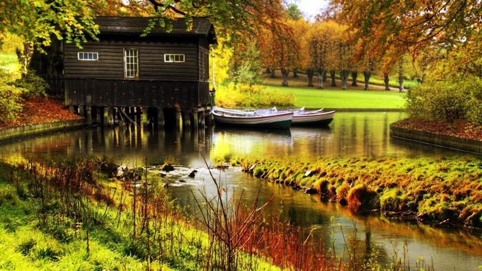 Autumn scene with boathouse and boats on a creek