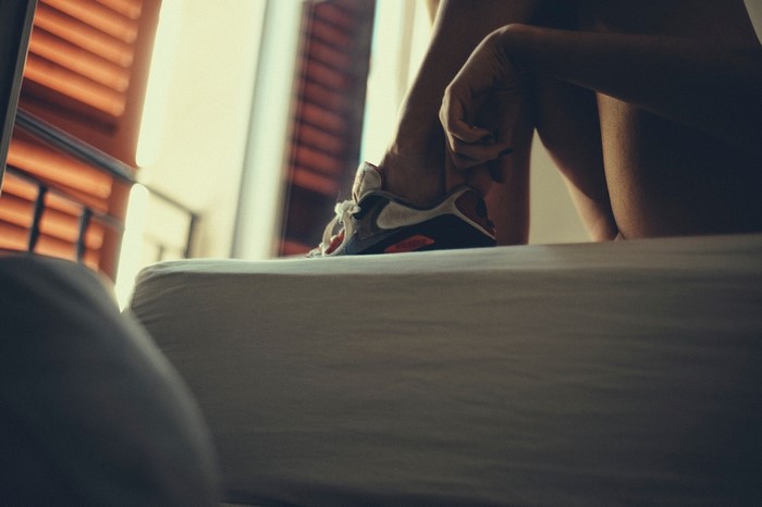 Woman tying shoe on bed