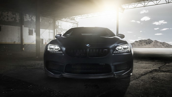 Matte black BMW M6 parked in an abandoned garage