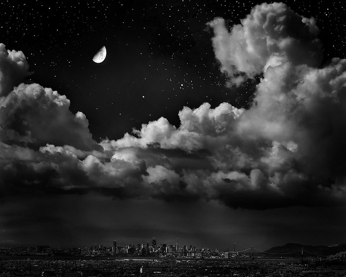 Night sky over a city skyline with clouds and moon