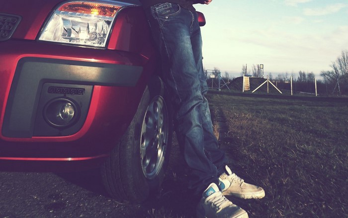 Person leaning on a red Ford Fusion car
