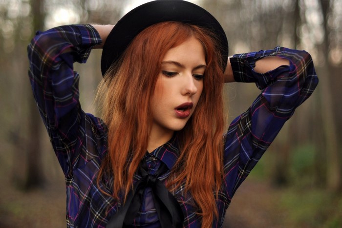 Woman with red hair wearing a hat and plaid shirt