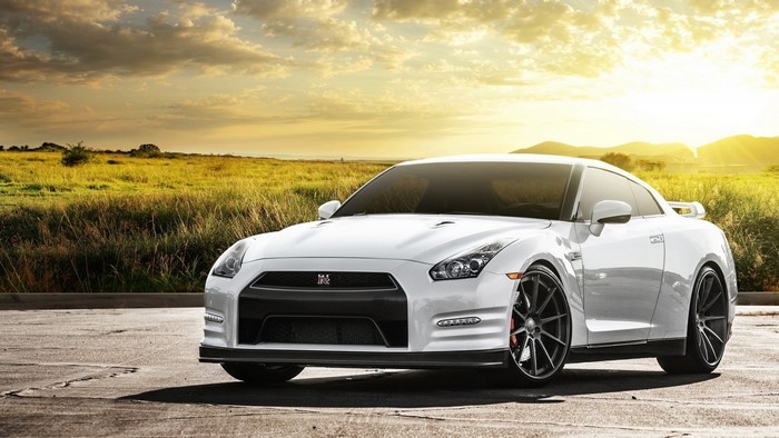 White Nissan GT-R parked on asphalt with field background
