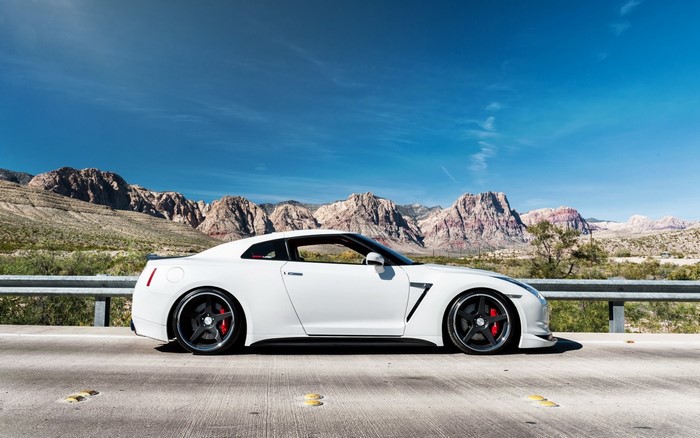 White Nissan GT-R parked on a road with mountains