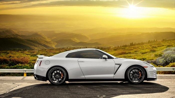 White Nissan GT-R parked on a mountain road at sunset
