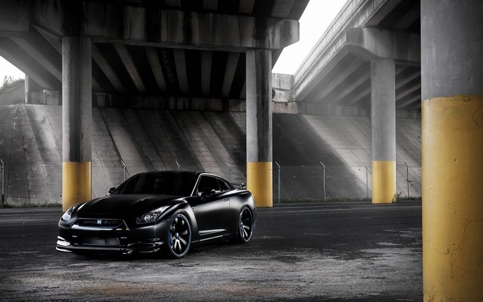 Black Nissan GT-R parked under a concrete overpass