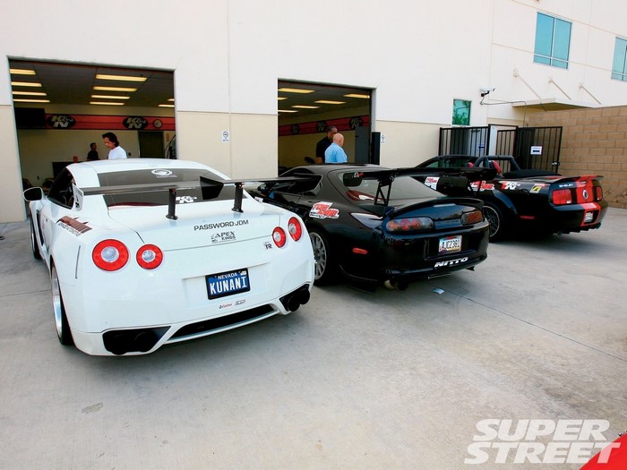 Three sports cars parked outside a garage