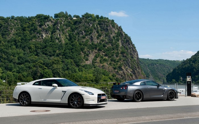 Two Nissan GT-R cars parked by a rocky mountain