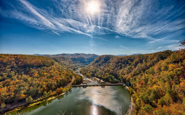 Autumn forest and river with a dam under a sunny sky