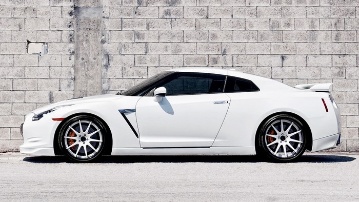 White Nissan GT-R parked against a brick wall