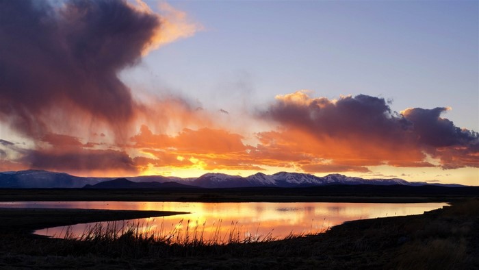 Sunset over mountains and lake with dramatic clouds