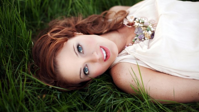 Redhead Woman Lying in Grass with Blue Eyes