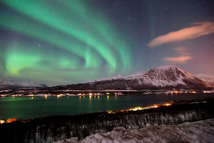 Aurora Borealis over a snow-covered mountain and fjord