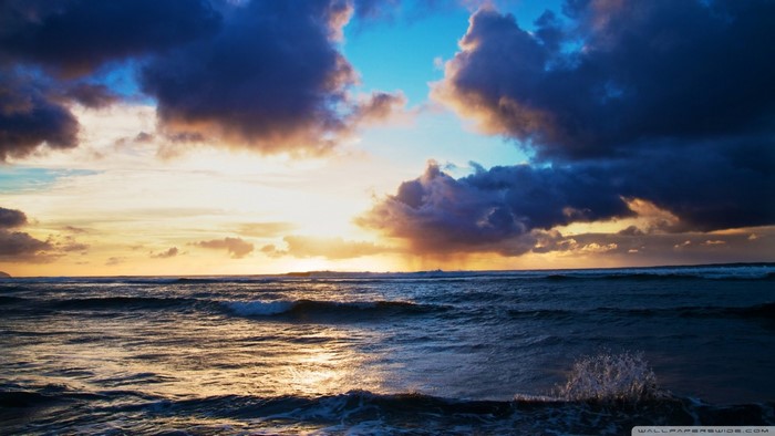 Sunset over the ocean with dark clouds and waves