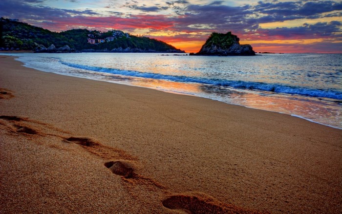 Sunset over a tropical beach with footprints in the sand
