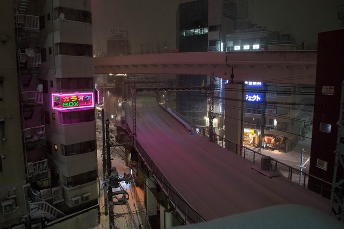 Snowy night in Japan with neon signs and elevated road
