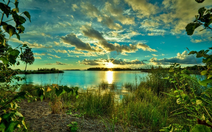 Sunset over a calm lake with trees and clouds