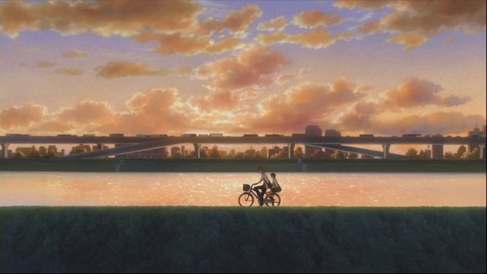 Couple cycling by river at sunset