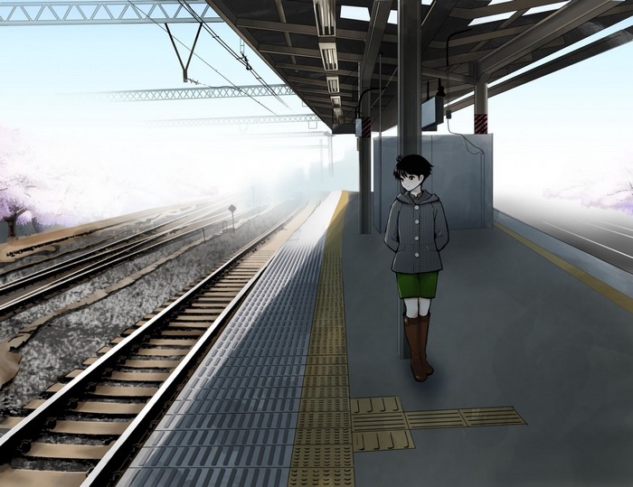 Person waiting at a train station with cherry blossoms