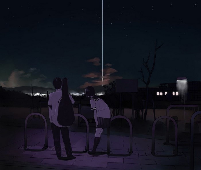 Two students watching a light beam in the night sky
