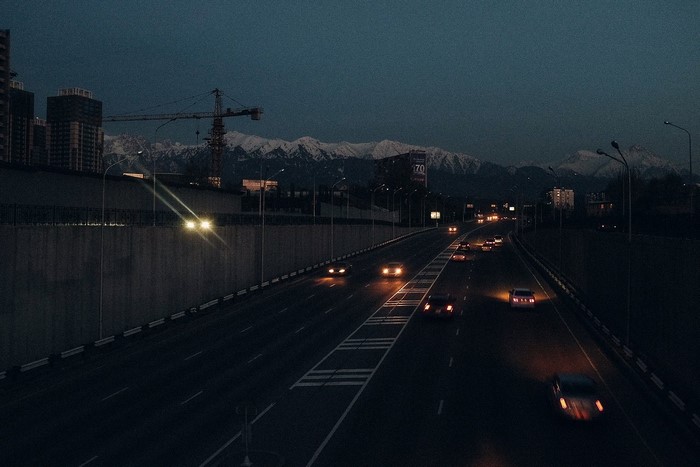 Highway at night with snow-capped mountains in the background