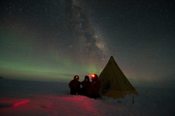 People camping under the Milky Way and Aurora