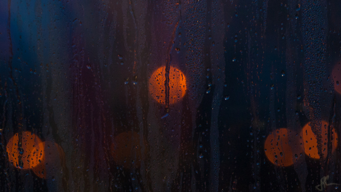 Bokeh lights through a rainy window at night
