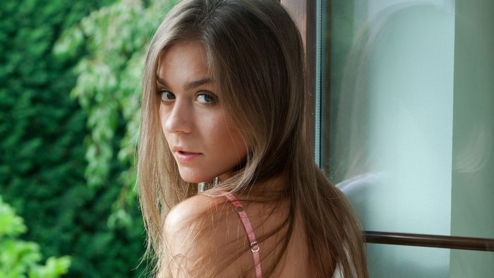 Woman with long brown hair looking over shoulder