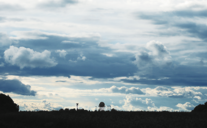 Radar dome on a hill under cloudy sky