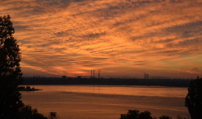 Sunset over water with industrial skyline