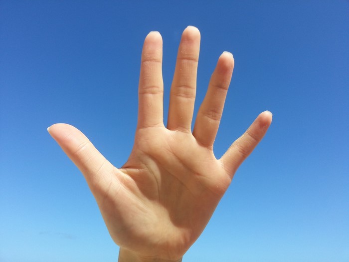 Hand held up against a blue sky
