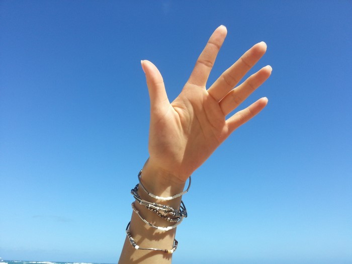 Hand with bracelets against blue sky and ocean