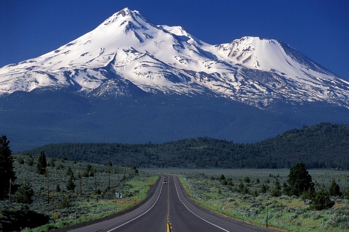Snow-capped mountain range with a road leading through a valley