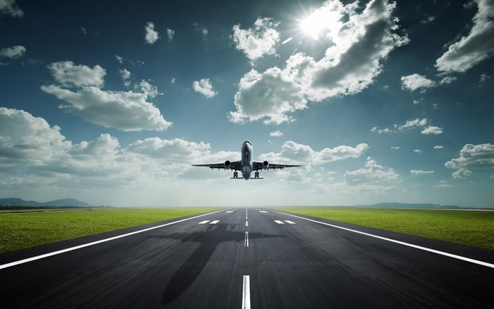 Airplane taking off from runway under cloudy sky
