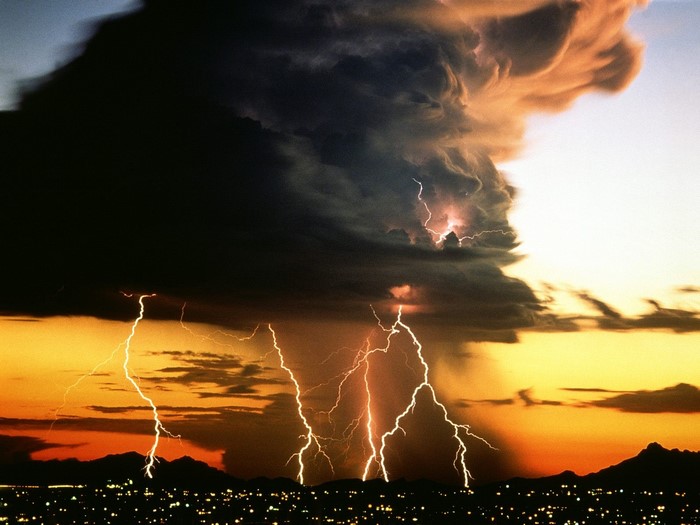 Lightning storm over a city at sunset