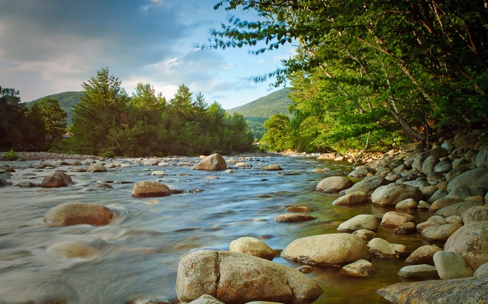 River flowing over rocks with trees and mountains