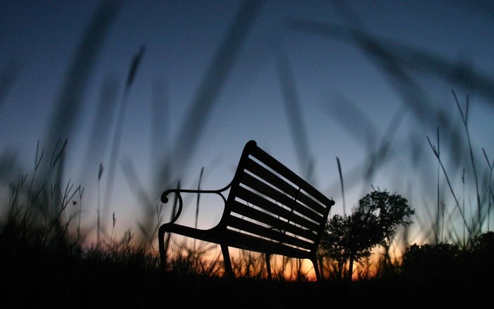 Silhouette of a park bench at dusk