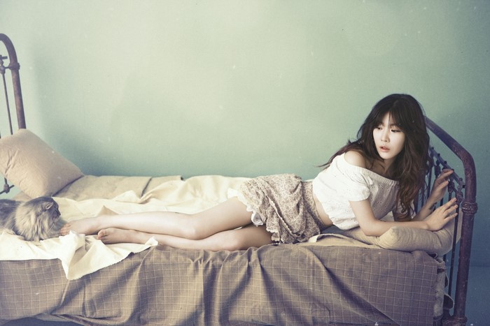 Korean girl with long hair lying on a bed with a cat