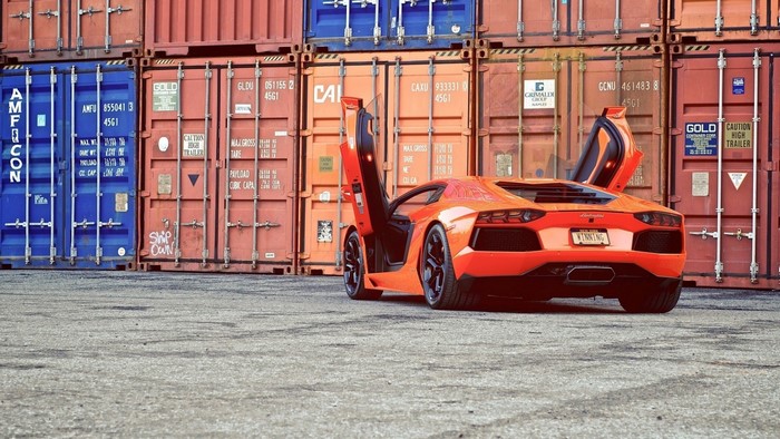 Orange Lamborghini Aventador parked by shipping containers
