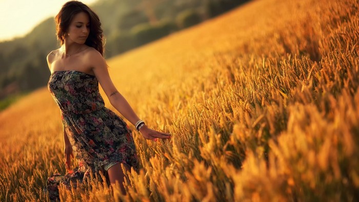 Woman in a floral dress in a wheat field at sunset