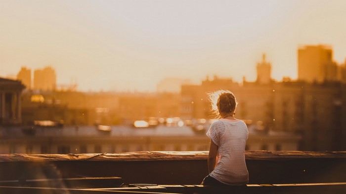 Woman sitting on a rooftop at sunset