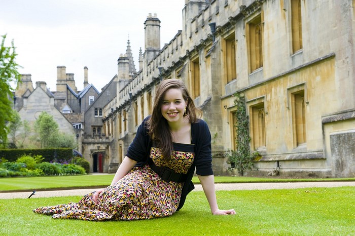 Anna Popplewell sitting on a lawn in front of a building