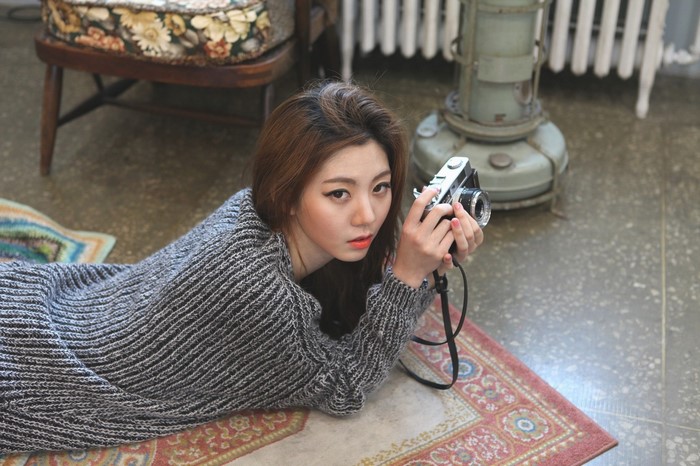 Woman holding a vintage camera, lying on a rug